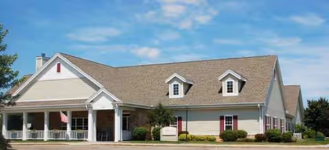 Single-story senior living facility with beige siding, white trim, and a welcoming front porch.