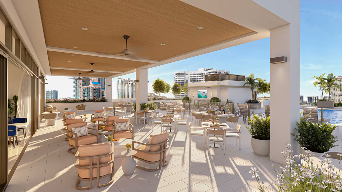 Outdoor covered patio area with multiple seating arrangements including cushioned chairs and tables set for dining, overlooking a cityscape with tall buildings and palm trees under a clear blue sky.