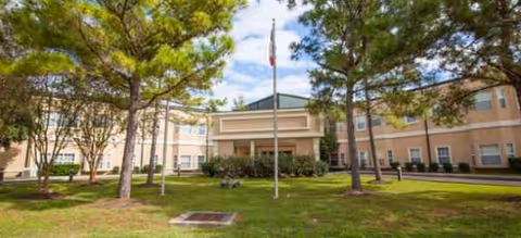 Front view of Reunion Court of Clear Lake showing entrance, flagpole, and trees.