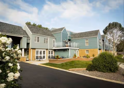 Blue, multi-unit assisted living building with landscaping and a parking lot.