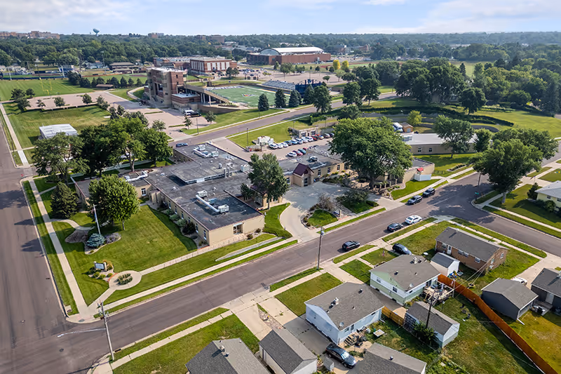 Aerial view of the Good Samaritan Society - Luther Manor campus and surrounding residential neighborhood, streets, lawns, and a nearby sports field.