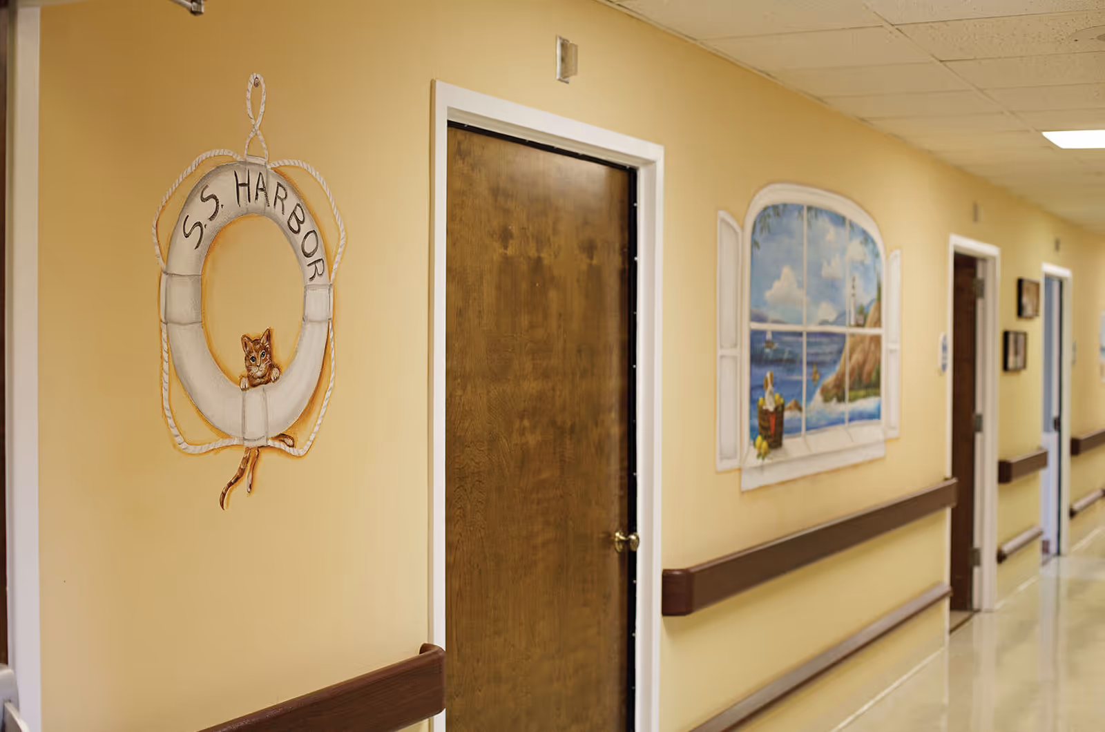 Interior hallway with beige walls, wooden doors, handrails and nautical-themed wall murals.