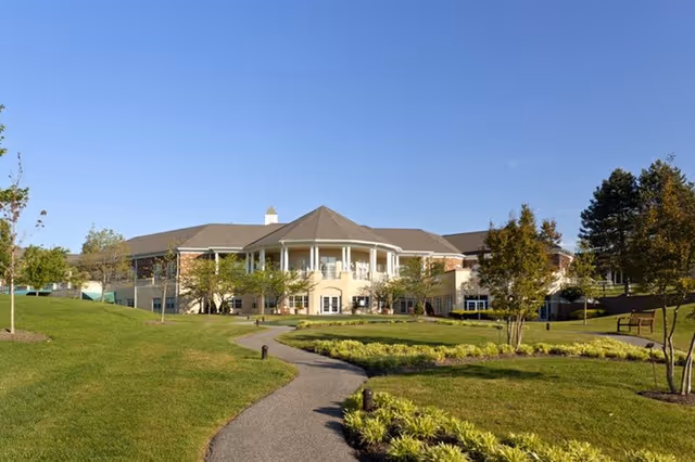 The Fairfax at Belvoir Woods stands behind manicured lawns and a winding path to the entrance.