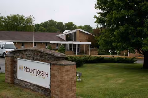 Mount Joseph sign in foreground with brick building, trees, and manicured lawn.