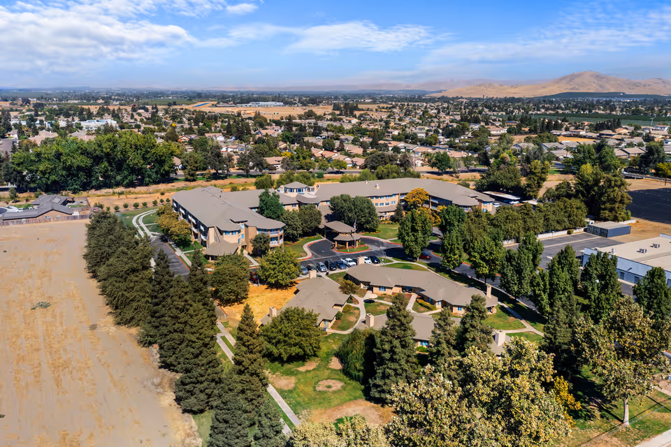 Aerial view of the Sierra Hills senior living campus with multiple residential buildings, parking areas, trees, and surrounding suburban landscape.