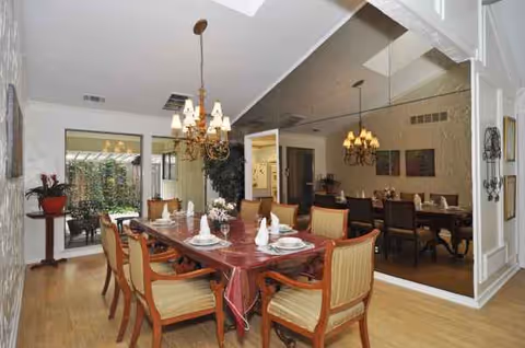 A spacious dining area with tables set for meals, warm lighting, and plants.