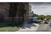 Exterior view of Cheltenham Nursing And Rehab Center with trees, sidewalk, and parked cars.