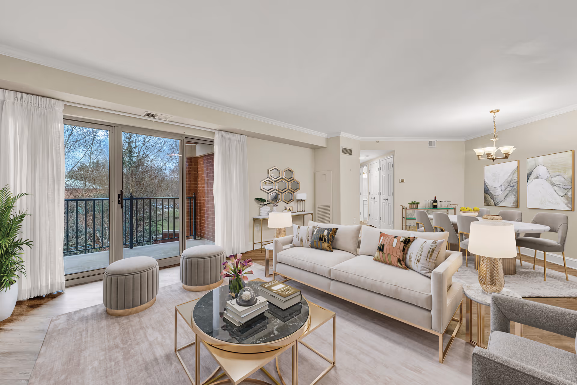 Bright open living and dining room with a sofa, coffee table, sliding glass doors leading to a balcony, and a dining table in the background.