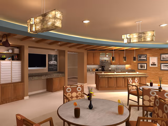 Communal dining and kitchen area with round tables, patterned chairs, wooden cabinetry, and pendant lighting.