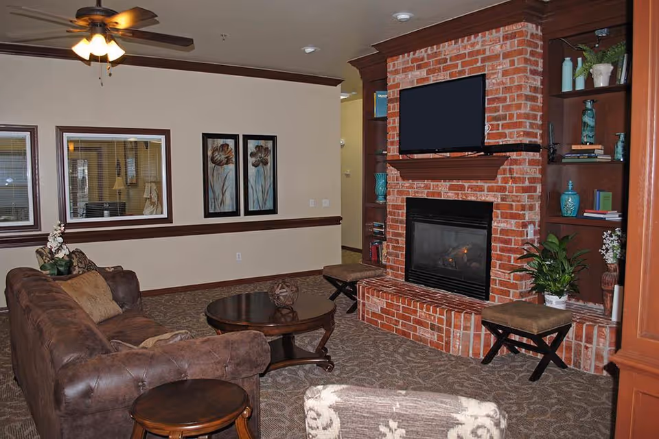 Cozy living room with a brick fireplace and mounted TV, sofa, coffee table, and built-in shelving.