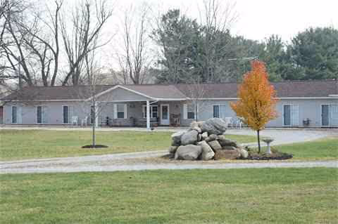 Exterior view of Silver Wings Assisted Living: single-story building with manicured lawn and rock feature.