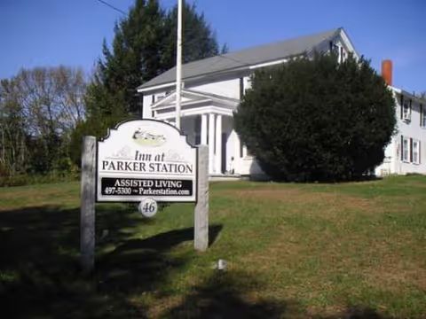 Exterior view of a white two-story assisted living building with a lawn sign.