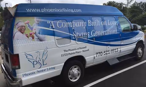 Blue and white Phoenix Senior Living van parked in a lot with slogan.