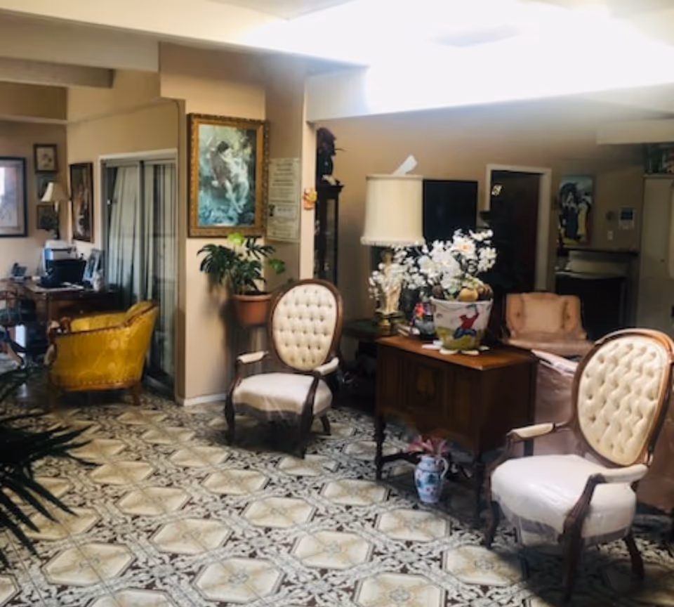 Cozy senior living interior lobby with vintage chairs, plants, and a floral centerpiece.