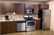 Kitchen area with dark wood cabinets, stainless steel appliances, and a mosaic tile backsplash.