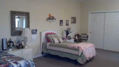Bedroom with a bed, dresser, mirror, and photos in a neutral suite.