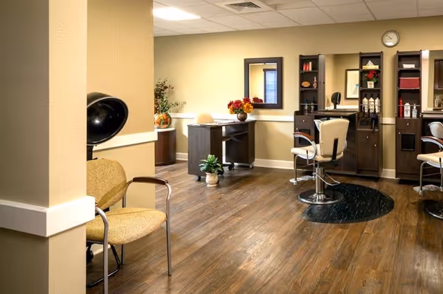 Interior salon area with styling stations, swivel chairs, a hooded hair dryer, and wood-look flooring.