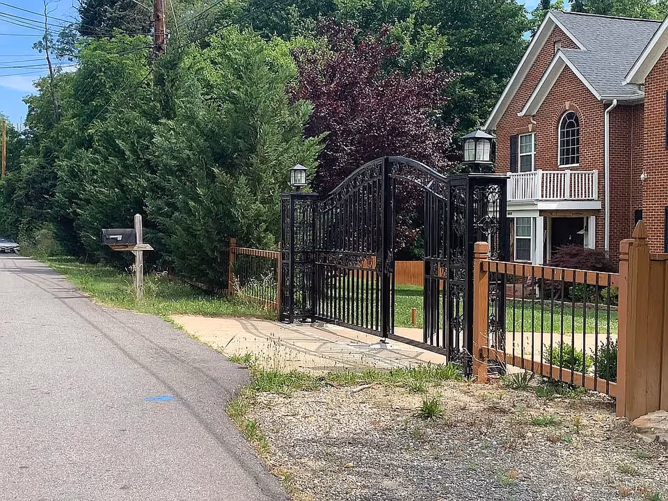 Sunshine Assisted Living brick building with black wrought-iron gate and wooden fence.