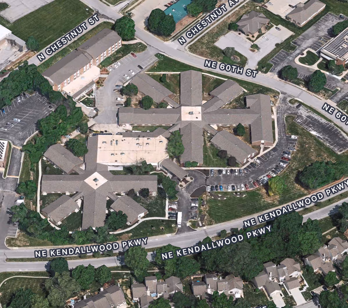 Aerial view of The Grand Royale Senior Living facility showing multiple interconnected buildings with star-shaped layouts, surrounded by parking lots, roads, and green spaces. Nearby streets include NE Kendallwood Parkway, NE 60th Street, and N Chestnut Avenue.