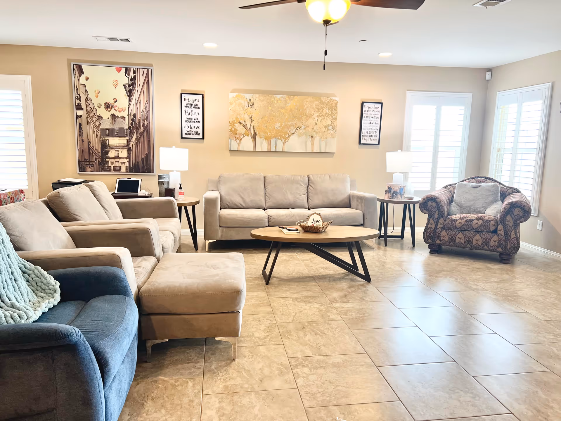 Bright, spacious living room with sofas, armchairs, a coffee table, and wall art.