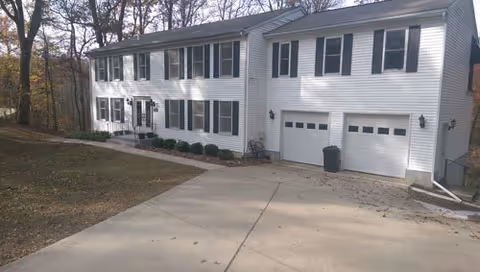 Two-story white building with two-car garage doors and a paved driveway.