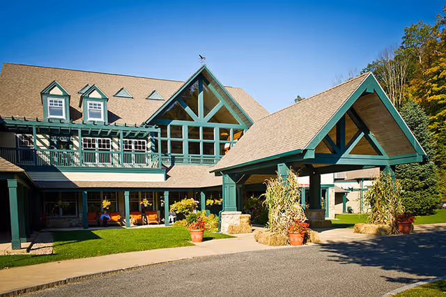 Geer Village Lodge exterior with green trim, peaked roofs, and potted plants at the entrance