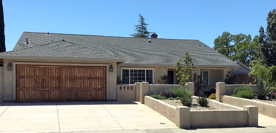 A single-story home with a two-car garage and desert-inspired front yard landscaping.