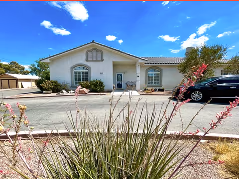 Front view of a single-story beige senior living home with desert landscaping.