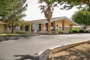 Single-story convalescent hospital building with a covered entrance, palm tree, and driveway.