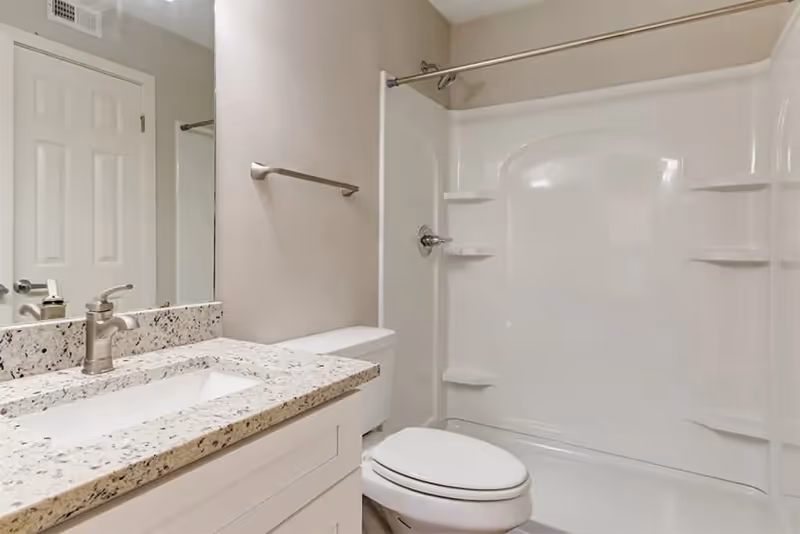 Clean bathroom with a vanity and granite countertop sink, toilet, and a bathtub/shower combo.