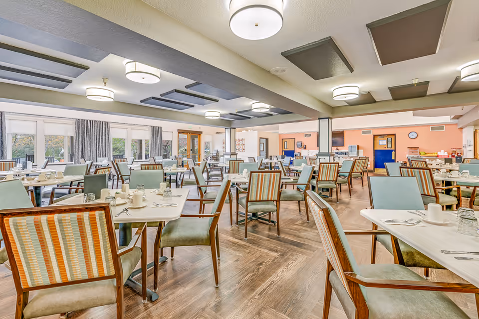 Bright, spacious dining room with multiple tables and chairs set for meals.