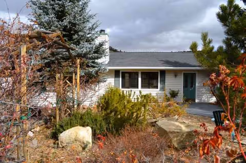 Single-story building with a landscaped front yard, trees, and shrubs in view.