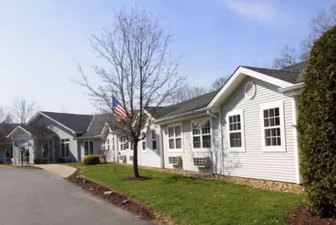 Exterior view of a Bayberry Place senior living building with white siding and flag.