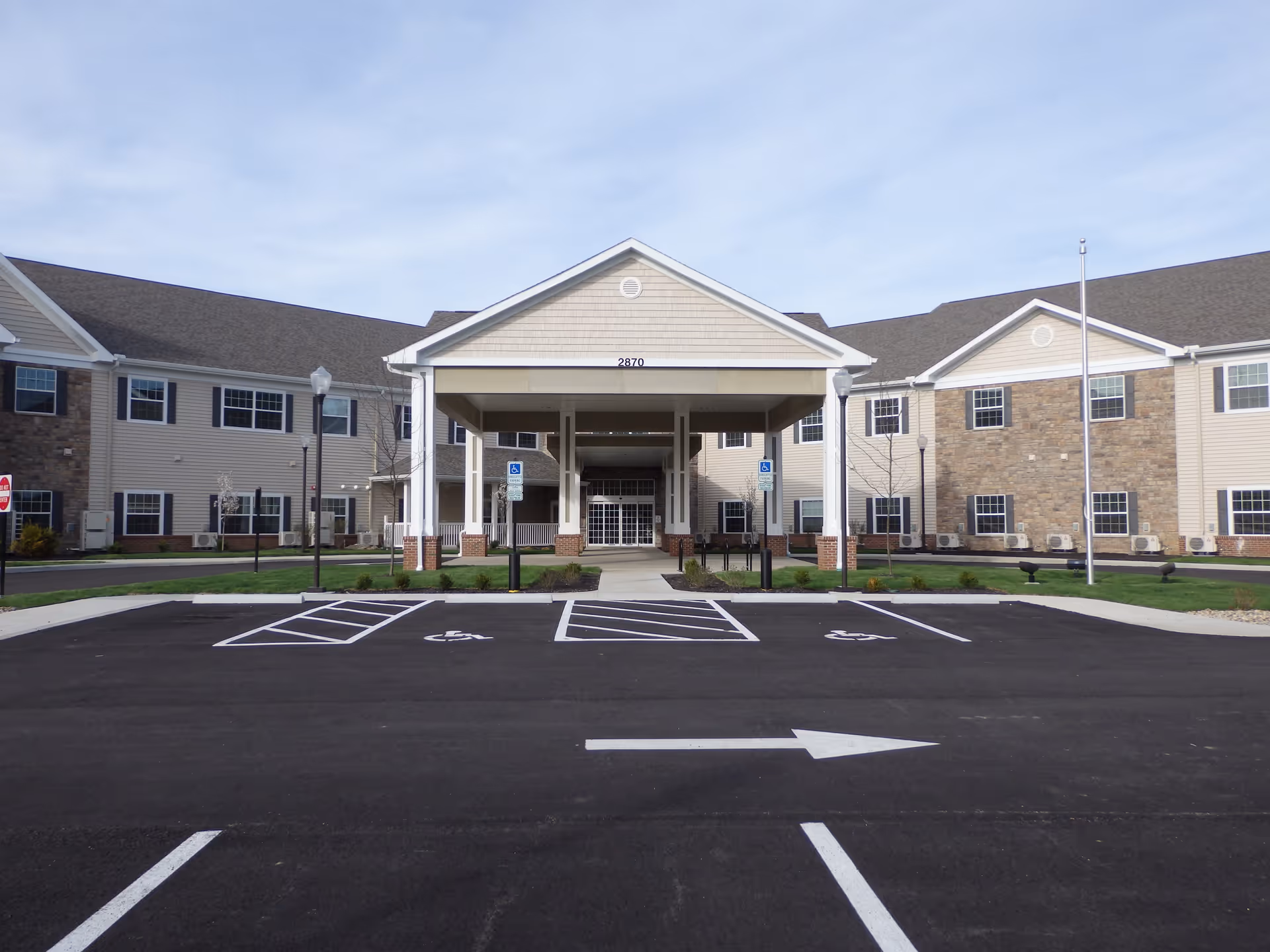 Front exterior view of Danbury Columbus facility showing a large covered entrance with columns, multiple windows, and a parking lot with handicap spaces in front.