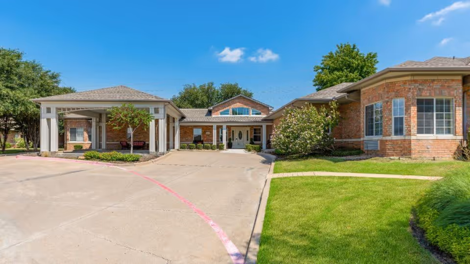 Exterior view of a single-story brick building with a covered entrance and well-maintained green lawn under a clear blue sky.