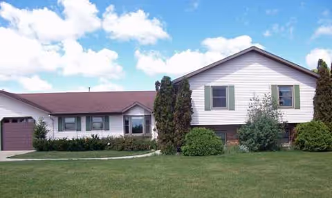 A single-story senior living facility with a manicured lawn and a driveway at the front.