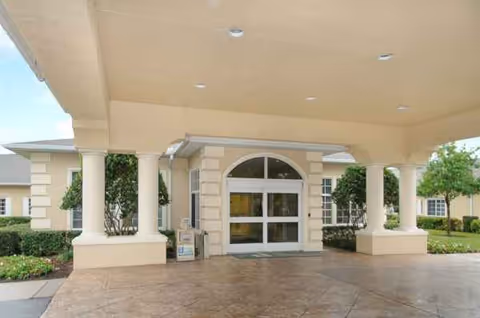 Covered porte-cochere entrance with columns at a senior living facility.
