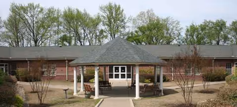 Front exterior of The King's Daughters and Sons Home, brick building with a portico and walkway.