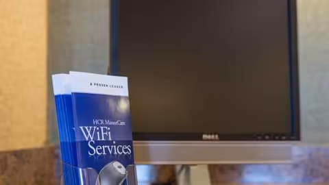 Dell monitor behind a blue WiFi Services brochure in a reception area.