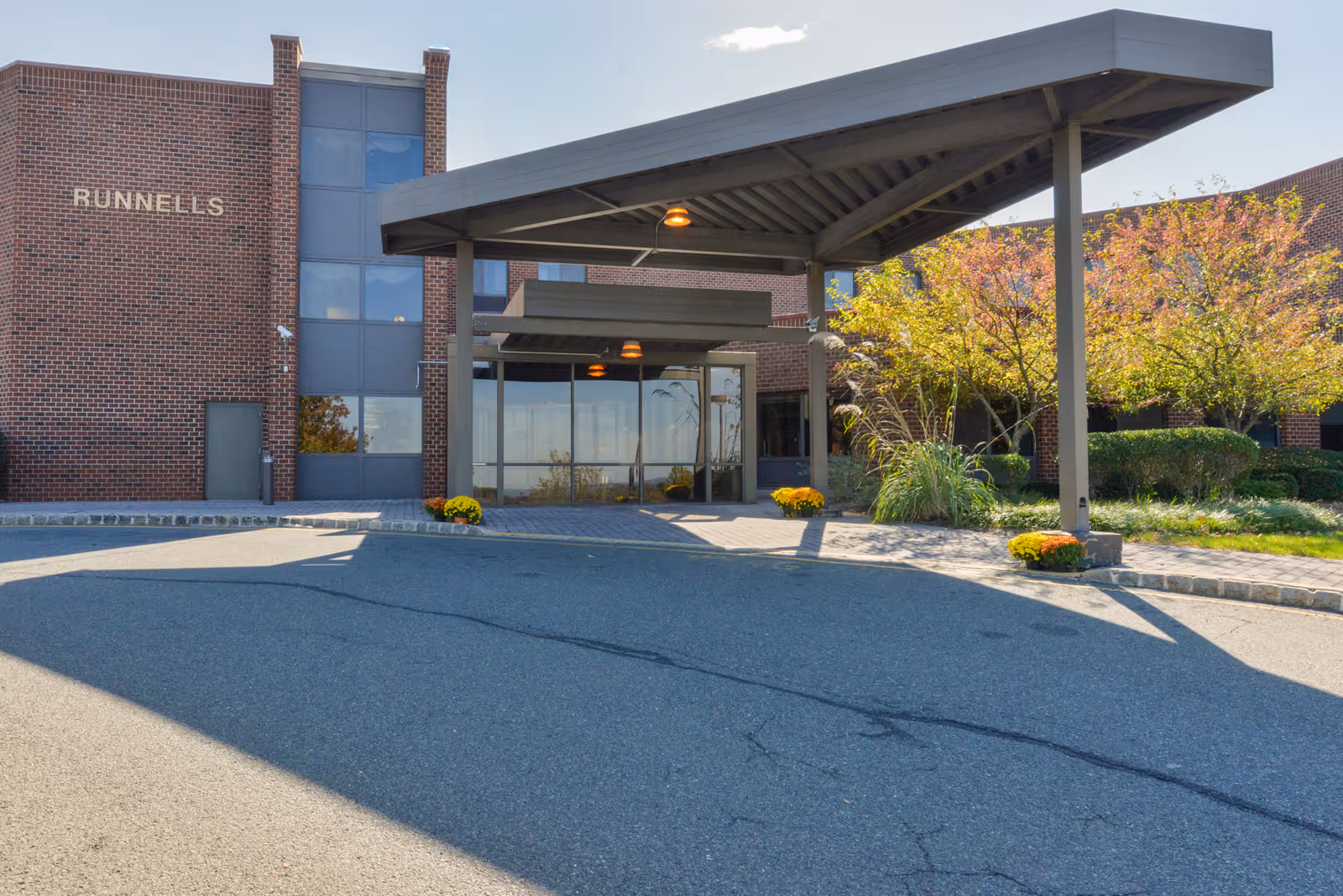 Front entrance of the Runnells healthcare facility showing a covered drop-off canopy, glass doors, and brick facade.