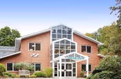 A brick senior living center with glass atrium entrance and green landscaping.