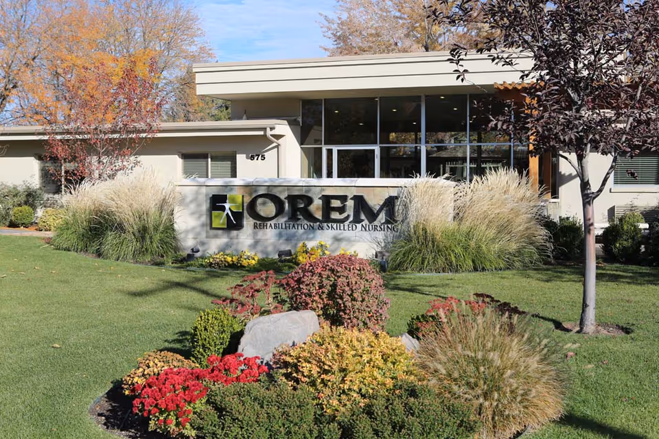 Front exterior of Orem Rehabilitation & Skilled Nursing showing the building sign and landscaped lawn.