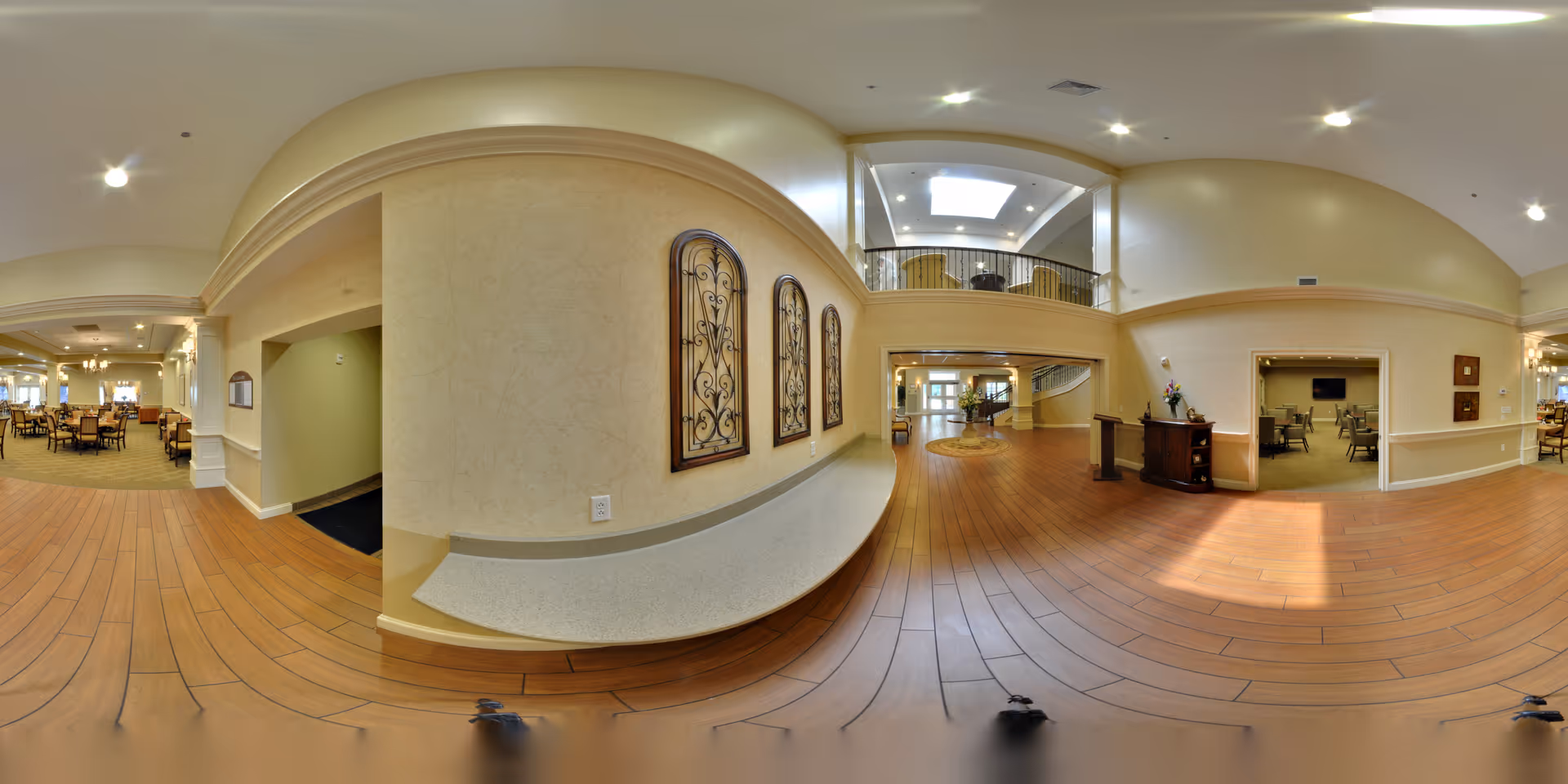 Spacious two-story interior common area with wood floors, seating and dining areas and an upper balcony.