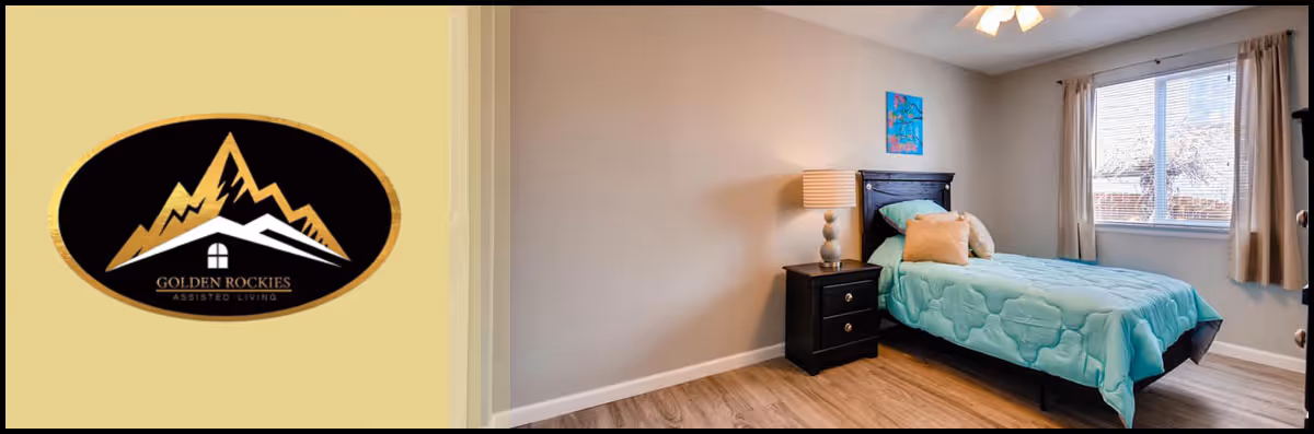 A simple bedroom with a single bed covered in a light blue quilt, a black nightstand with a lamp, a window with beige curtains, and a small colorful painting on the wall. The floor is wooden, and the room has neutral-colored walls.