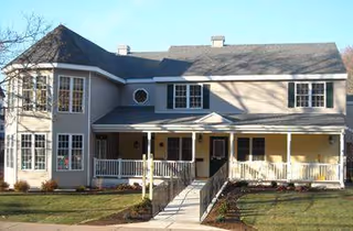 Two-story senior living building with a wraparound porch at Char Laine Manor.