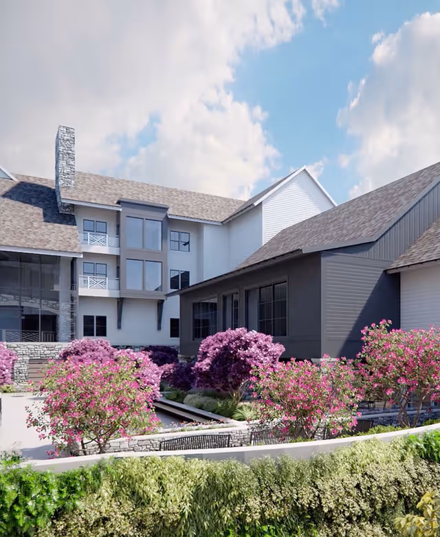 Exterior view of a multi-story residential building with a landscaped courtyard and blooming pink shrubs.