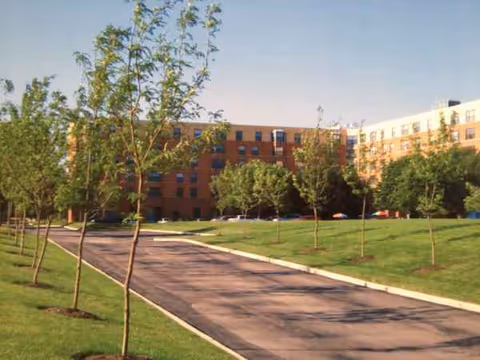 Park Plaza Retirement Center exterior with lawn, trees, and a paved driveway