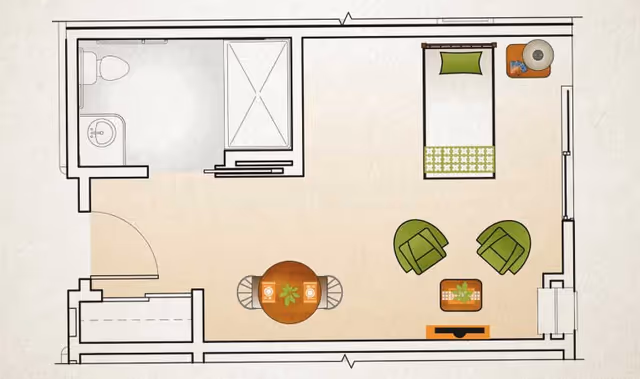 Floor plan of a small living space at Morningside Place showing a bedroom area with a single bed, nightstand with a lamp, two green chairs around a small table, a round dining table with two chairs, and a bathroom with a toilet, sink, and shower.