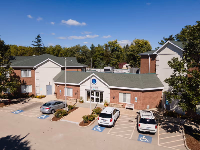 A brick senior living facility front with glass doors and accessible parking spaces.
