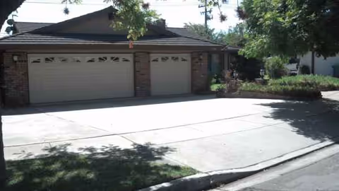 Front exterior of a brick assisted living facility with a wide driveway and garages.